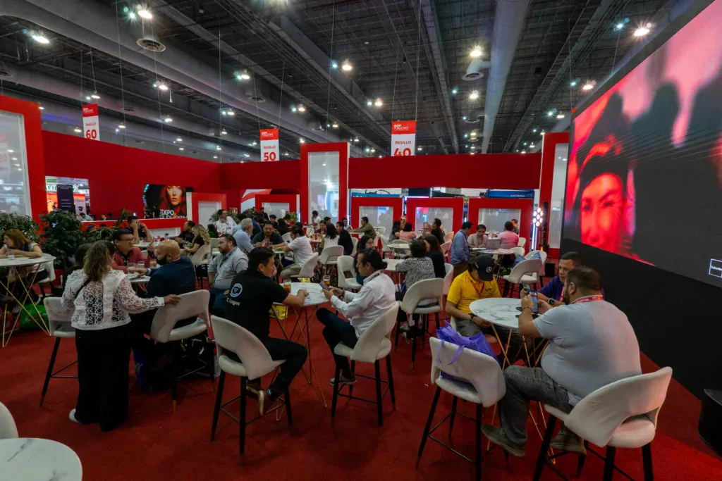 area-de-stands-y-networking-en-expo-publicitas-durante-la-exposicion Escena del piso de exhibición en ExpoPublicitas, con visitantes interactuando en la zona de stands y áreas de networking al cierre del recorrido.