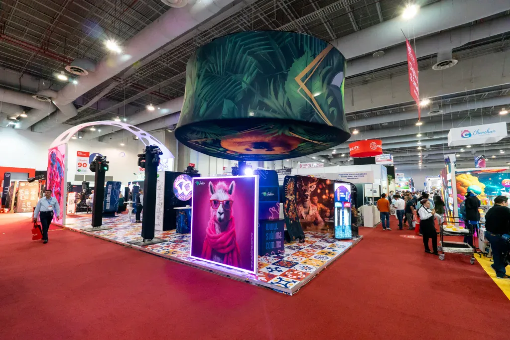 Stand BTL con diseño abierto y alto impacto visual que utiliza iluminación, gráfica y formatos envolventes para atraer al público y facilitar la circulación en un entorno de exposición profesional.