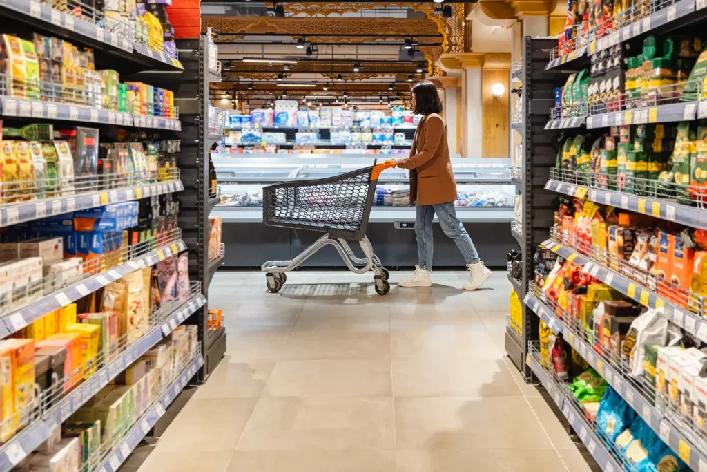 Consumidora recorriendo un supermercado moderno, representando la evolución de las cadenas retail y la experiencia de compra dentro del comercio minorista. 