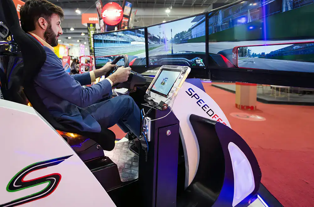 Visitante prueba un simulador de conducción integrado al recorrido del stand, una experiencia que atrae su atención y facilita el acercamiento comercial.